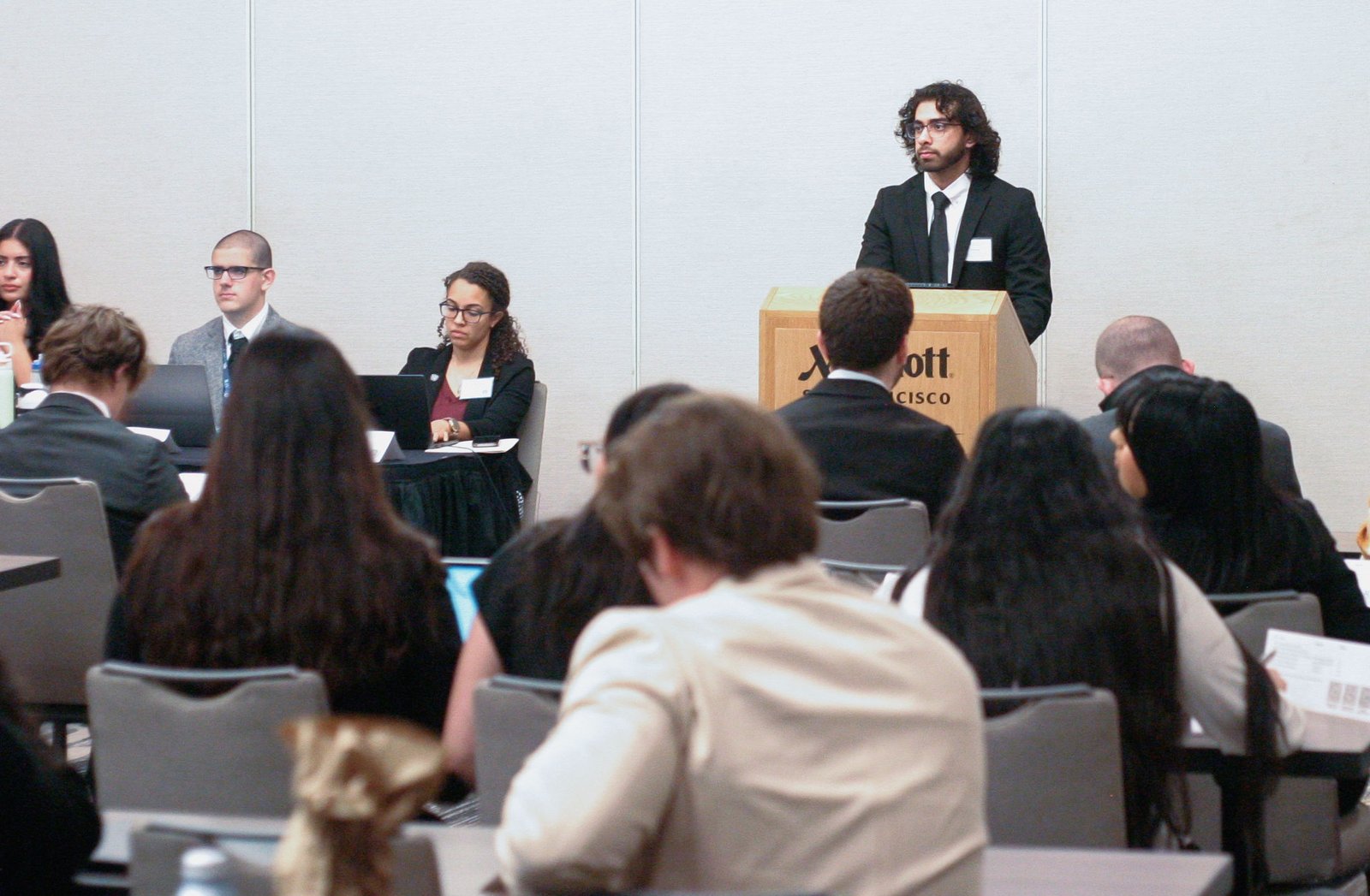 Hamed Emari speaking at a podium during a Model UN conference